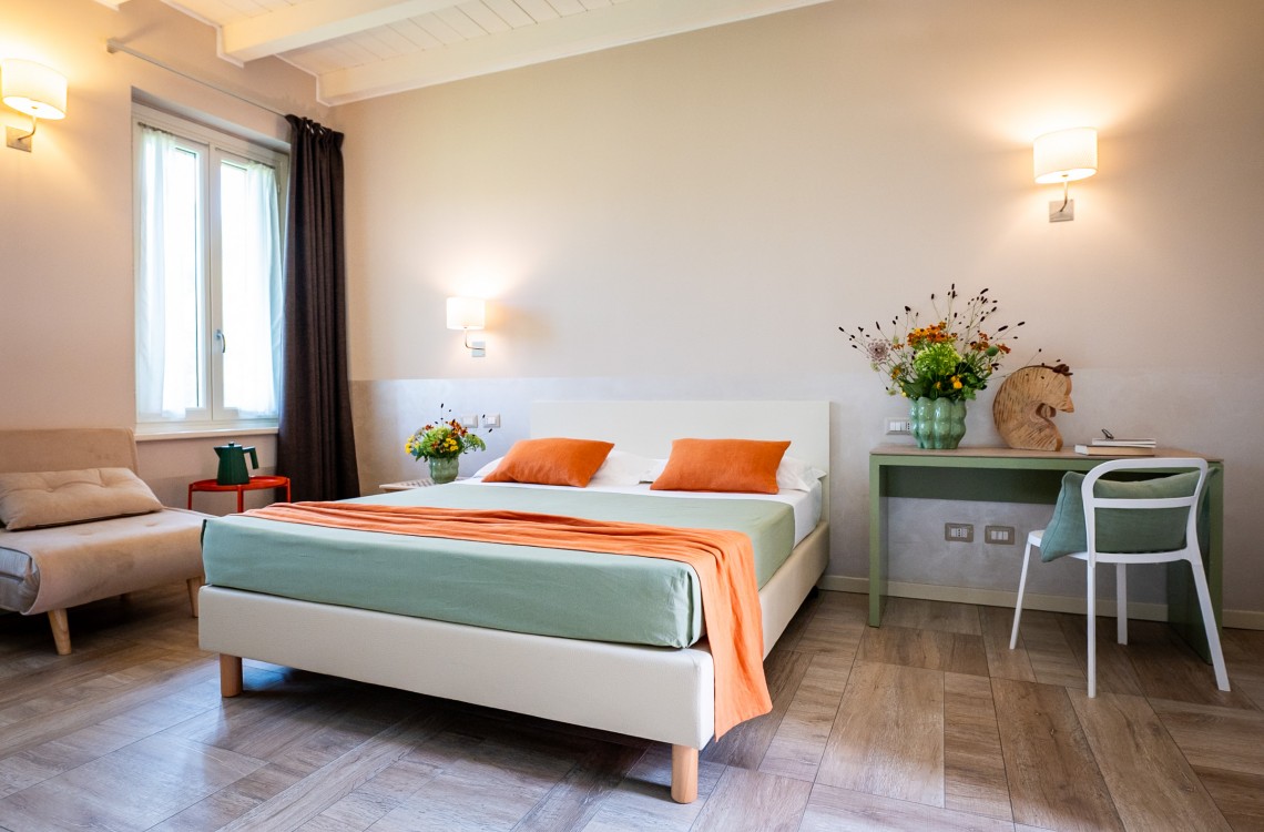 Disposta al piano primo dell'edificio lungo la balconata aperta verso la corte interna, camera doppia con letto matrimoniale, anche ad uso singolo, ampia e luminosa e stata pensata per essere il luogo ideale dove trascorrere il vostro soggiorno di vacanza o di lavoro. Di complessivi 30mq circa, è arredata con stile contemporaneo, caldo ed elegante, dispone di scrivania e confort di ultima generazione. Gode ​​di una bellissima vista sugli edifici circostanti e sulla campagna. <br>Con letto matrimoniale, disponibile uso SINGOLA e uso DOPPIA<br>