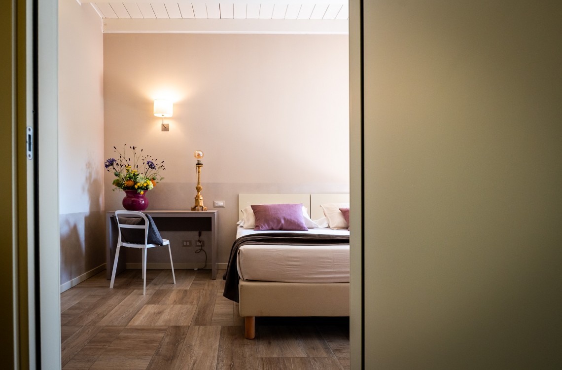 Disposta al piano primo dell'edificio lungo la balconata aperta verso la corte interna, camera doppia, anche ad uso singolo, ampia e luminosa è stata pensata per essere il luogo ideale dove trascorrere il vostro soggiorno di vacanza o di lavoro.  Di complessivi 30mq circa, è arredata con stile contemporaneo, caldo ed elegante, dispone di scrivania e confort di ultima generazione. Gode ​​di una bellissima vista sugli edifici circostanti e sulla campagna. <br>Con letto matrimoniale o due letti singoli, disponibile uso SINGOLA e uso DOPPIA<br>